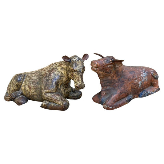 Pair of 19th century Guatemalan carved wooden nativity animals, depicting a recumbent horse and ox. Both figures retain traces of their original polychrome - the horse in mottled cream and brown, shows simple incised detailing to the mane, while the ox, in warm reddish brown with traces of blue and black at the hooves, features applied wooden horns and a slightly upturned gaze.  Folk-carved with rustic charm characteristic of rural Guatemalan devotional art, these figures once accompanied a large nacimiento